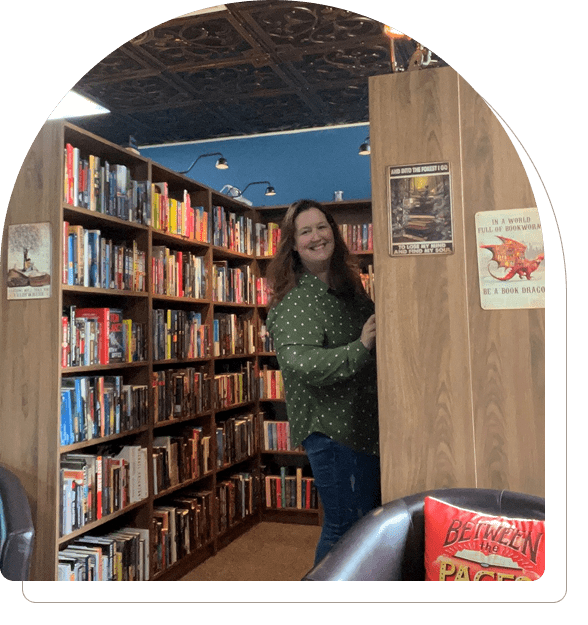 Person browsing books in a cozy library aisle.